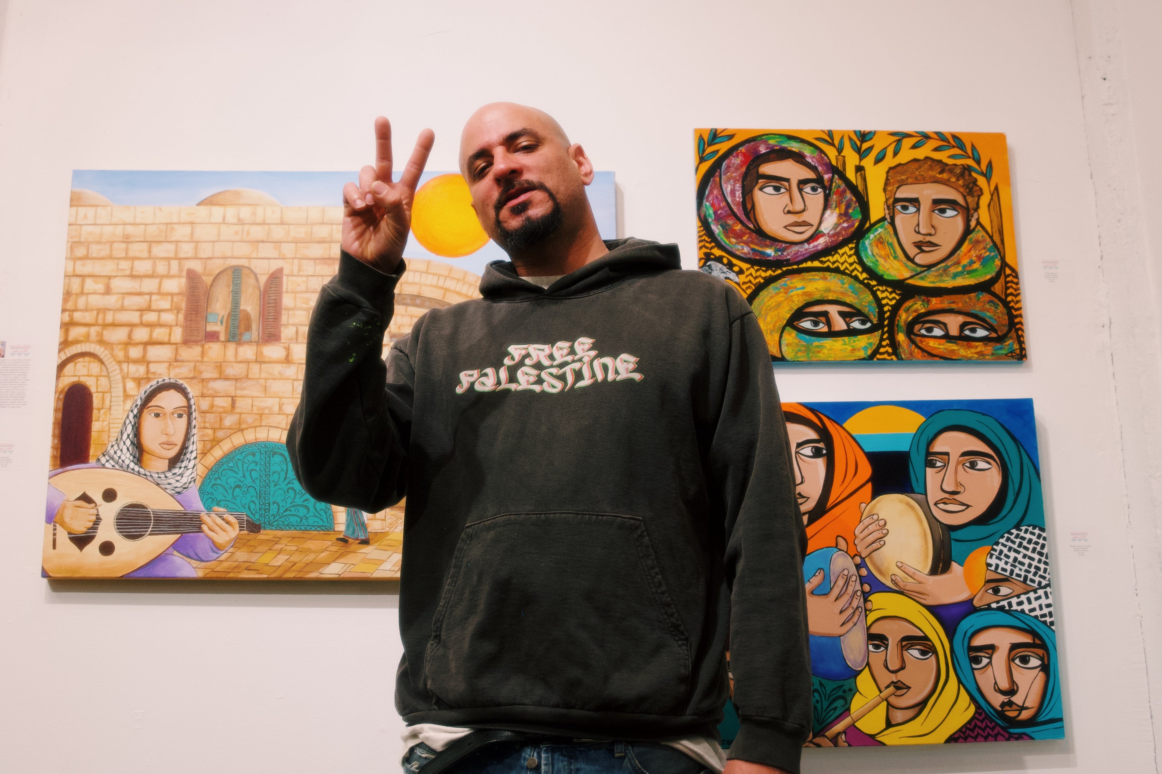 Person wearing a 'Free Palestine' hoodie in front of artwork on a wall