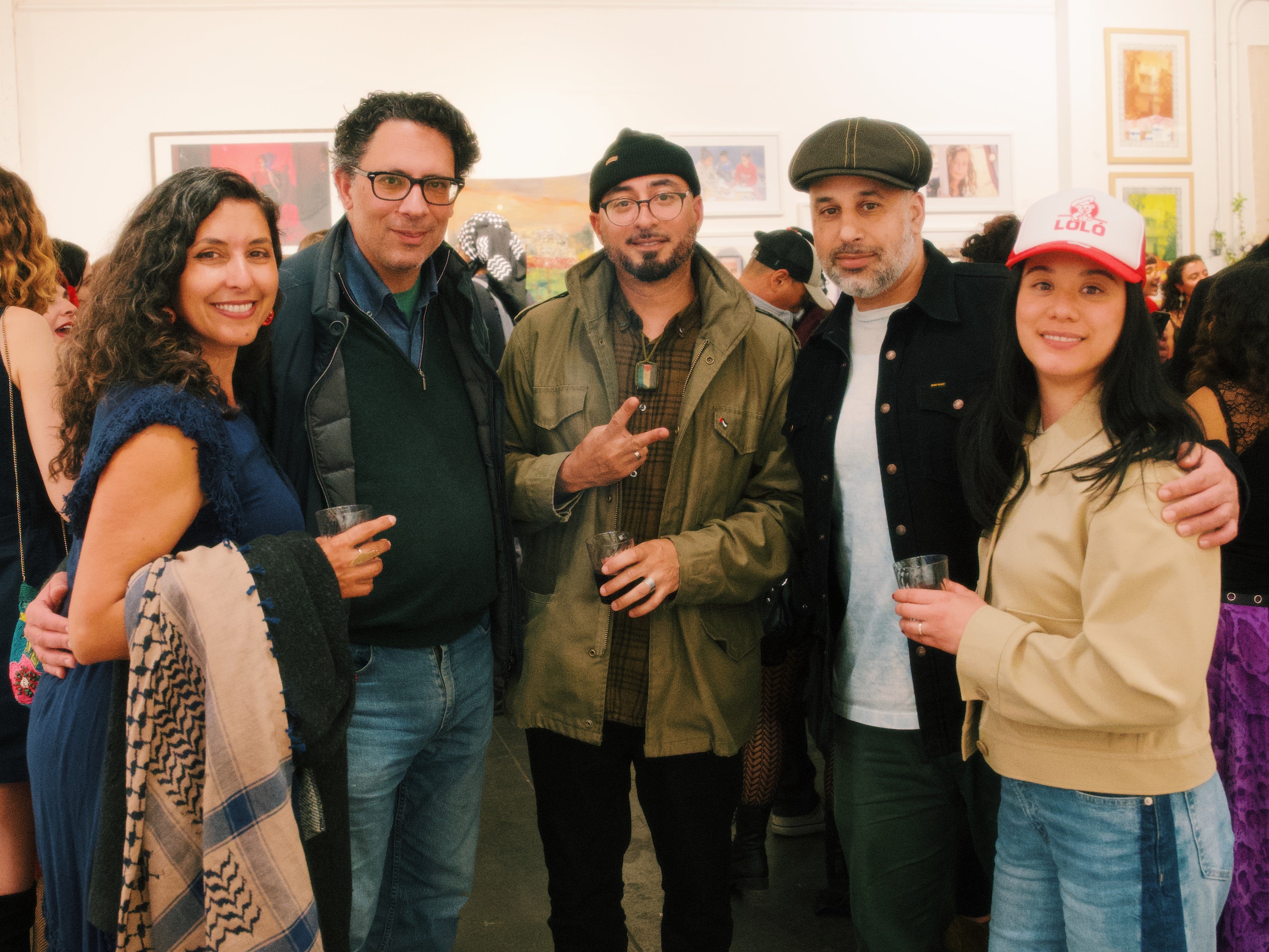 Group of people standing together in a social setting, possibly an event or gathering.