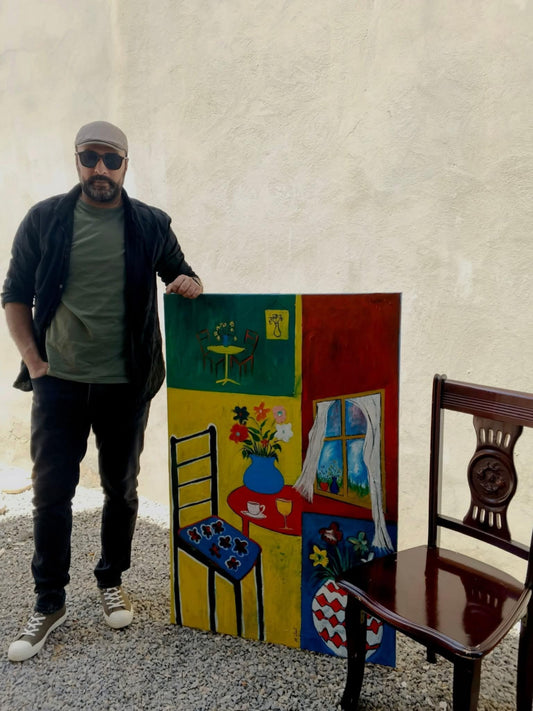 Picture of Muftah Elsheref standing next to his painting titled Color Dialogue in a Quiet Corner