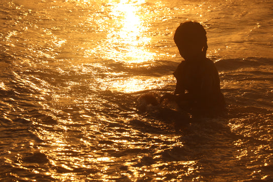 Silhouette of a child in the water at sunset at Gaza Beach